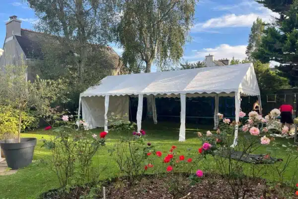 Barnum 4x8 ouvert, installé dans un jardin fleuri.
