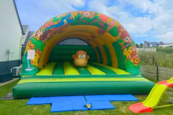Jeu gonflable pour enfant installé dans un jardin. Vue de face.